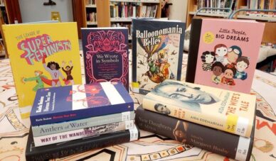 Books stacked on a table, including kids' books, books by Scottish women writers and an anthology of works by African women writers