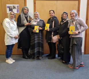 A group of women stand together holding books title The Mismatch