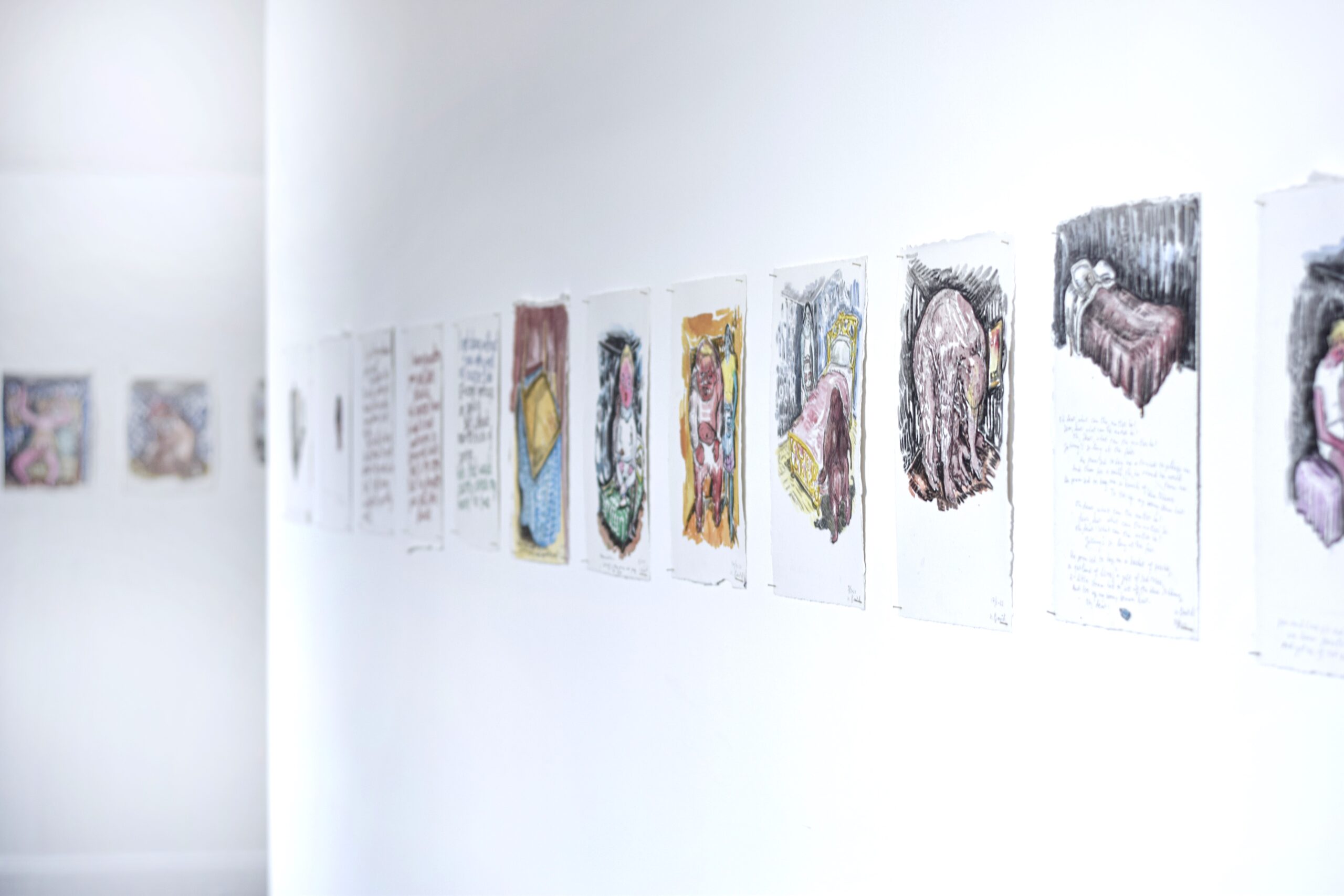 Exhibition view showing a row of 12 water colour art works with mixture of handwritten texts and images on torn paper pinned to the wall. In the distance a second wall with similar sized images can be seen.