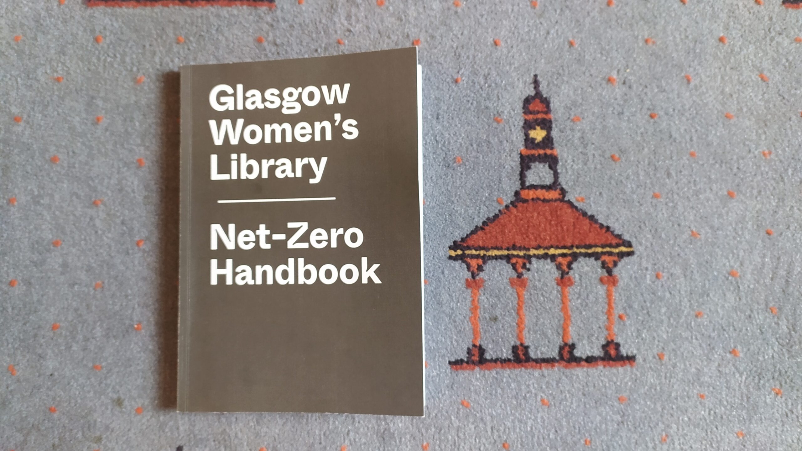 A copy of GWL's Net-Zero Handbook, lying on the library's 'Bridgeton Umbrella' carpet