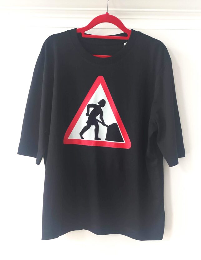 Black T-shirt with the Women at Work' logo, featuring a stylised woman digging