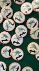 Several round badges with names on them are pinned to a green felt board.