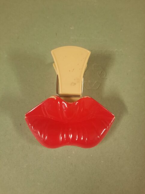 Photo of a large clip or clothes peg with a large plastic red lips stuck to the front