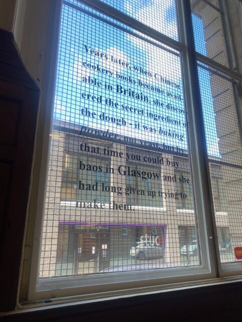 Photo shows vinyl window text ona window at the Glasgow Women's Library that reads ' years later, when Chinese cookery books become available in Britain, she discovered the secret ingredient of the dough- it was baking powder, not yeast, but by that time you could buy baos in Glasgow and she had long given up trying to make them.'