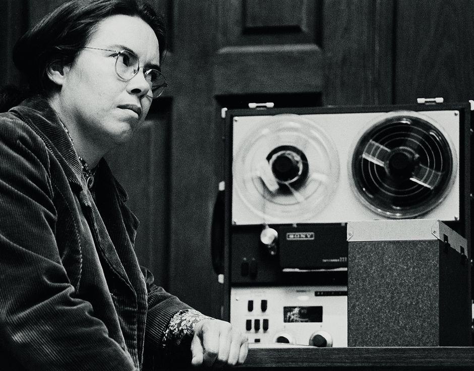 Black and white photo of Pauline Oliveros in her studio with analogue recording equipment