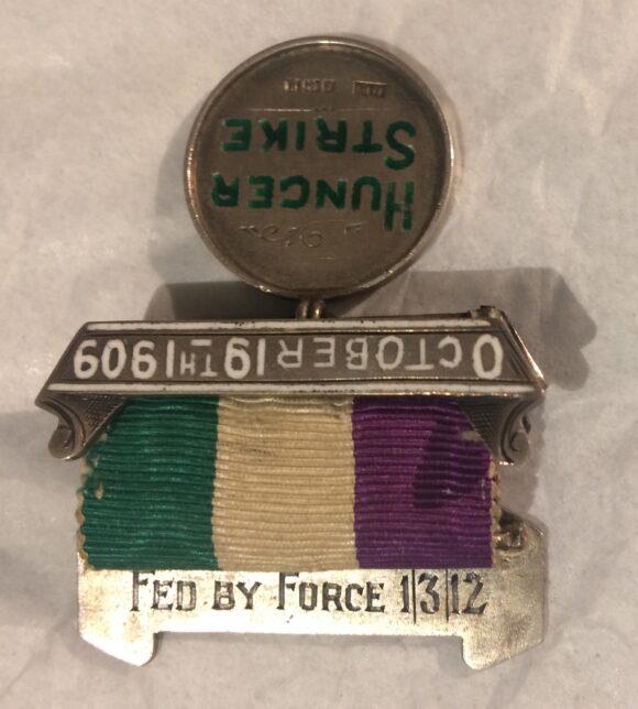 Detail of the hunger strike medal, showing an inscription on the back of one of the bars which reads 'Fed by Force 1/3/12'