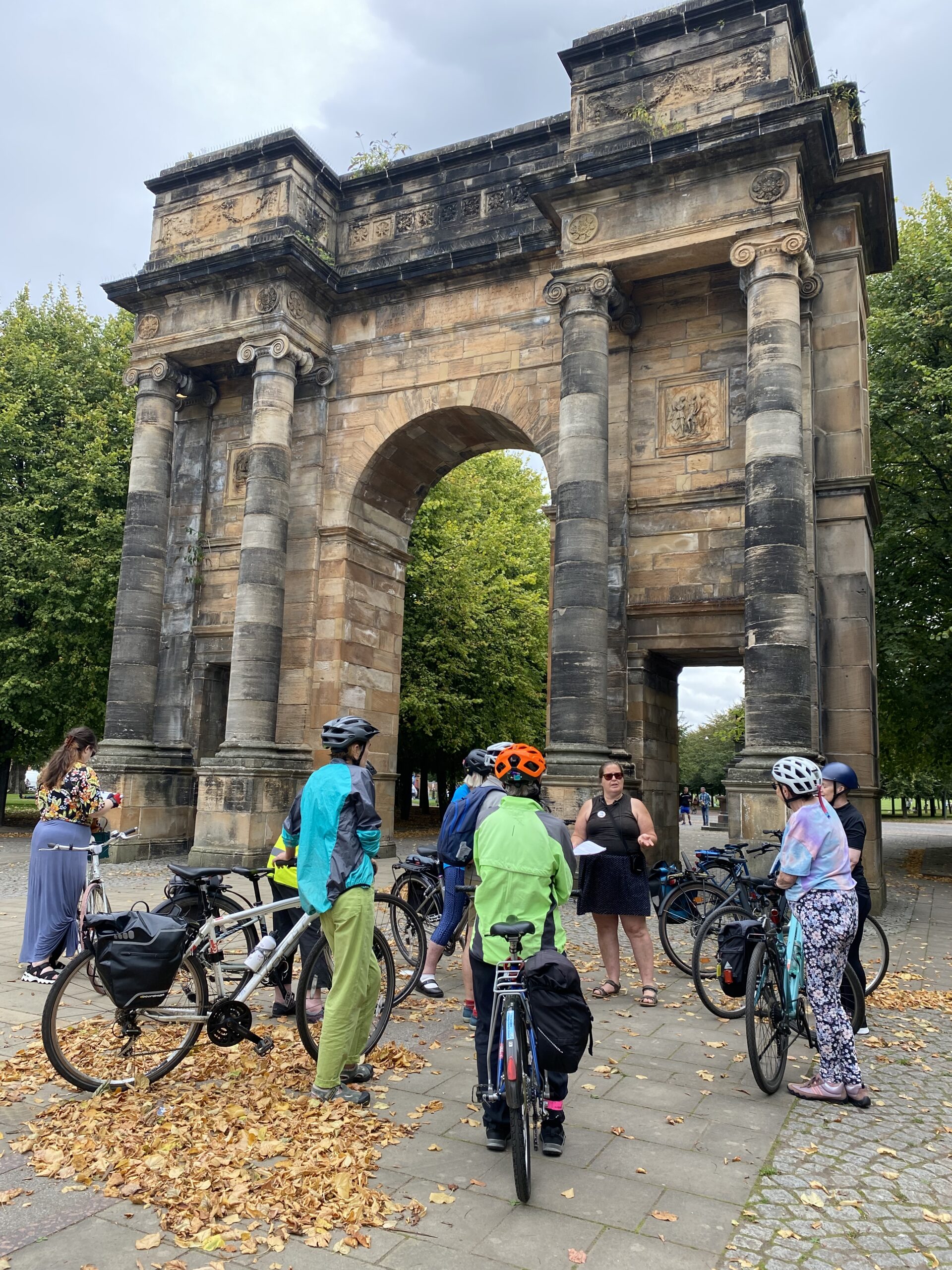 Cyclists with bikes gather around a tour guide.