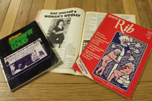 Spread of the book 'Spray It Loud' by Jill Posener and two issues of the feminist magazine 'Spare Rib' from 1982, one open to a knitting pattern and the other closed to show the cover.