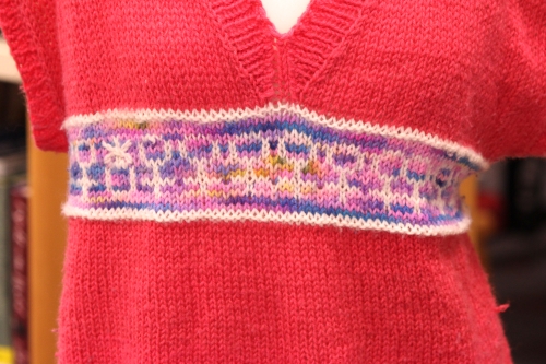 Close up of the central band of the pink jumper with a venus symbol motif.