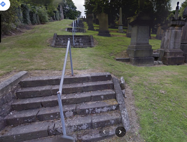 5 flights of 6 old stone steps with a handrail down the middle of them. They go up a grassy slope with tombstones to the right.