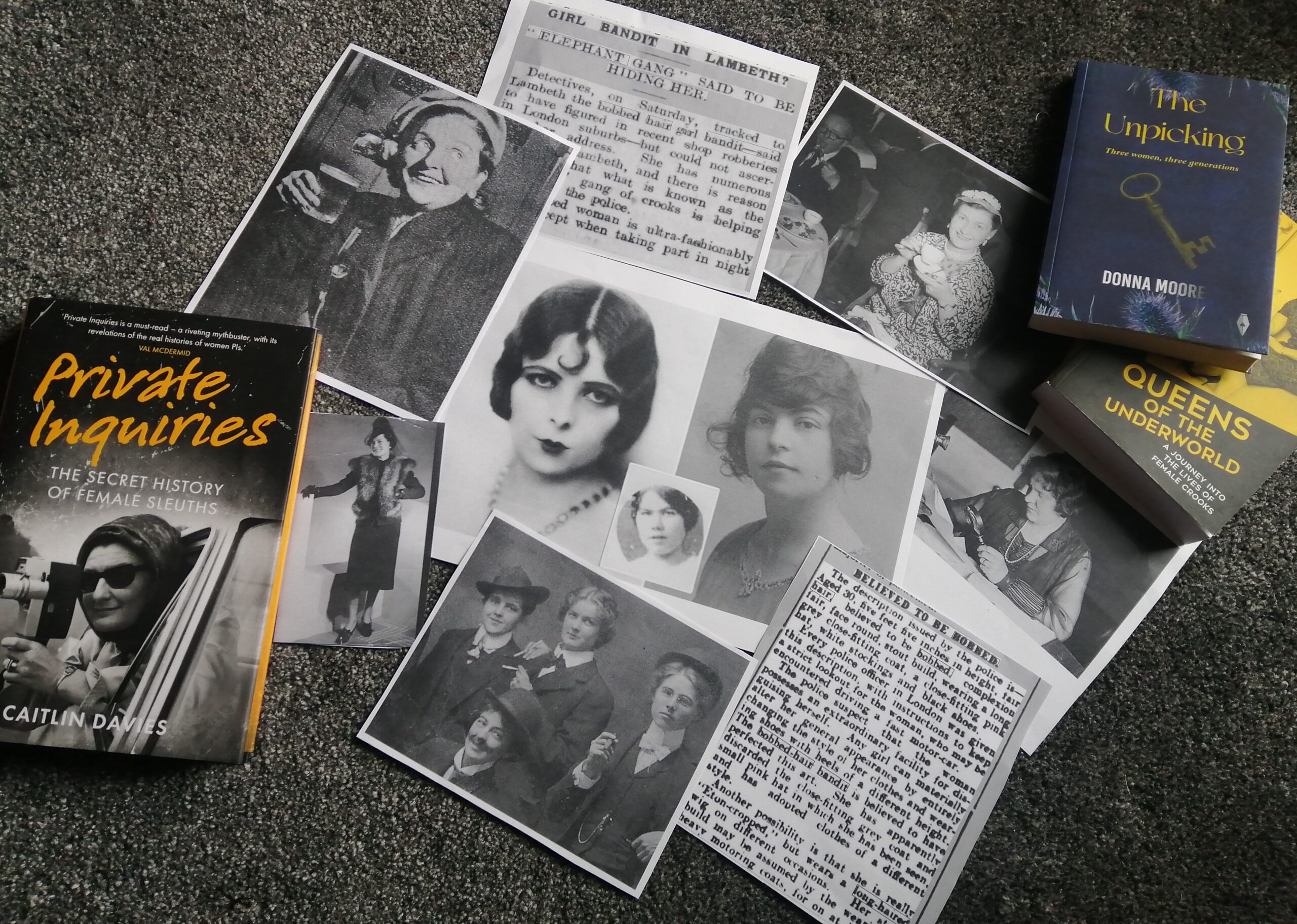 A colour photograph of a selection of black and white photographs, scanned newspaper records, and two books laid out on a carpeted floor.