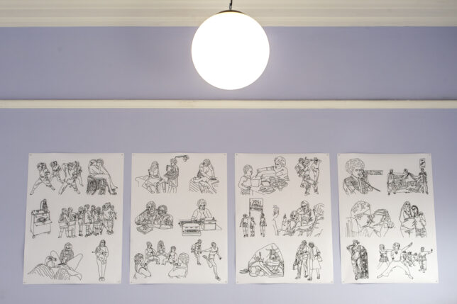 Photo of community room with illustration posters on lavender wall.