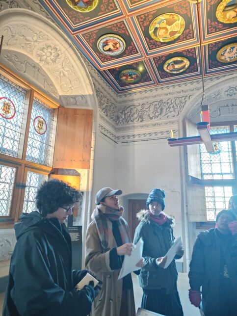 Readers gathered together in The Palace Apartments, depicting stained glass windows and richly decorated ceilings.