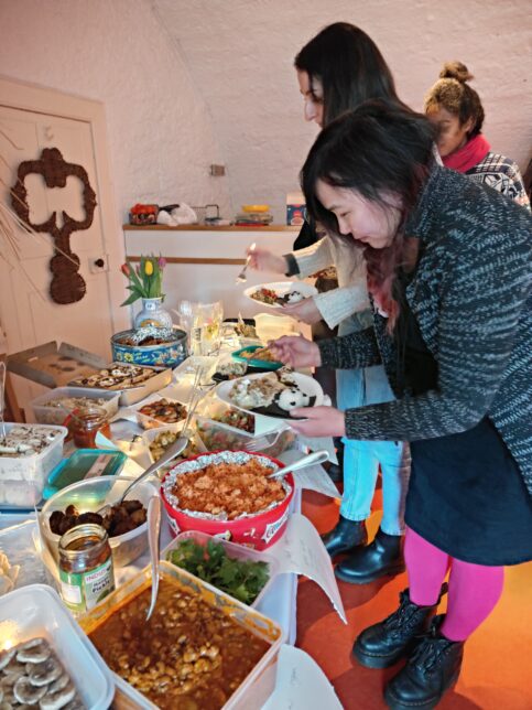 A few readers serving up plates of food from the wide variety of dishes brought. Some dishes pictured: A bean curry, jollof rice, green salad, roasted vegetables and mango pickle.