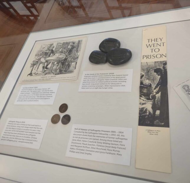 Different artifacts relating to the Suffragettes on display in a glass case.
