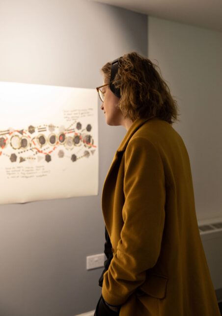 A woman looking at an exhibition. She looks absorbed and focused.