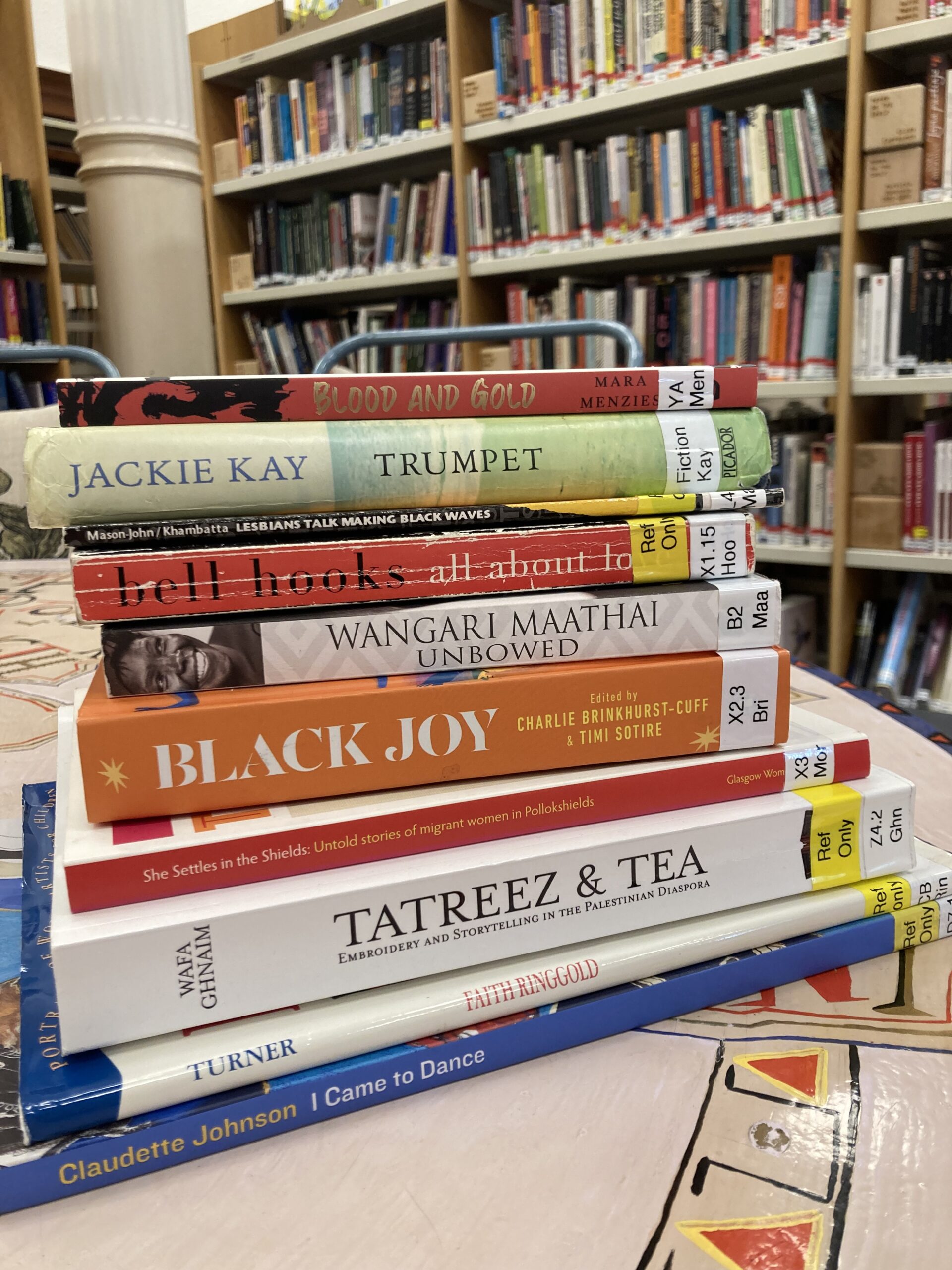 A pile of books written by Black writers and selected from the GWL collection, stacked on a table in the library.