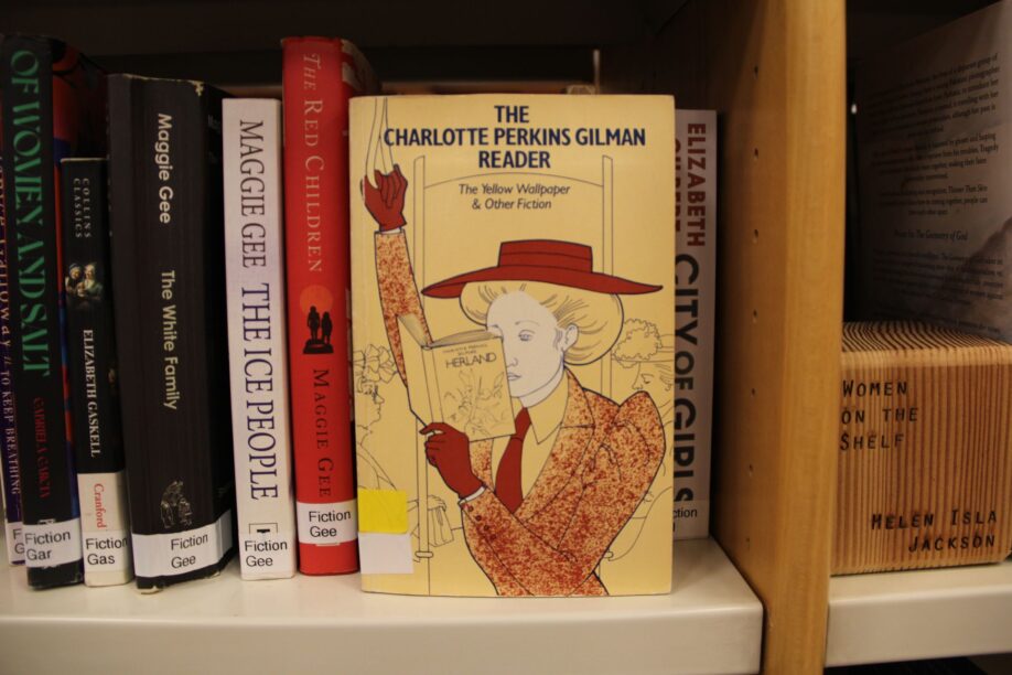 Image of the short story "The Yellow Wallpaper" by Charlotte Perkins Gilman which is in front of other books