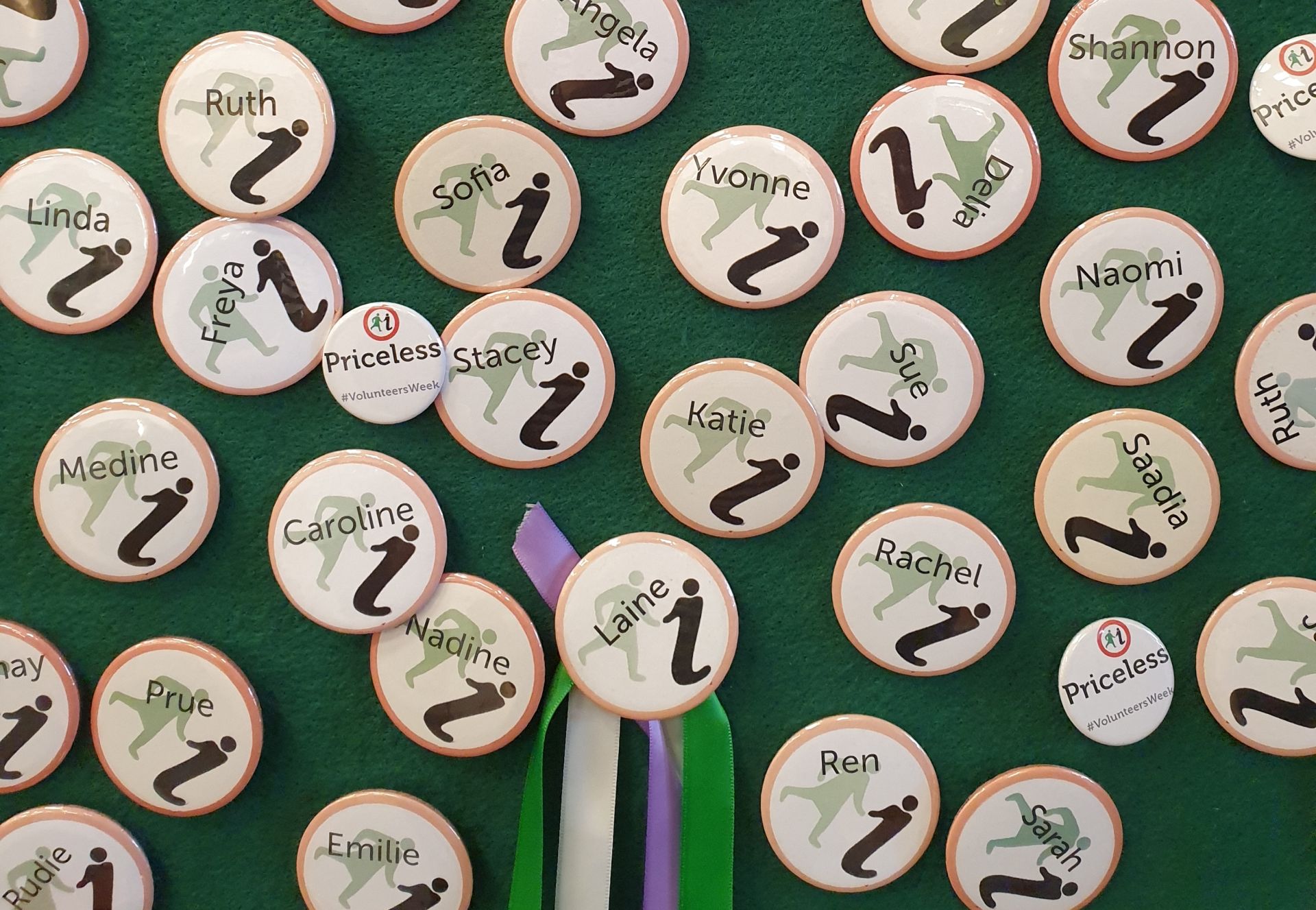 Glasgow Women's Library volunteer name badges on a green felt background. Names include Katie, Sofia, Nadine, Saadia, Freya, and Medine amongst others.