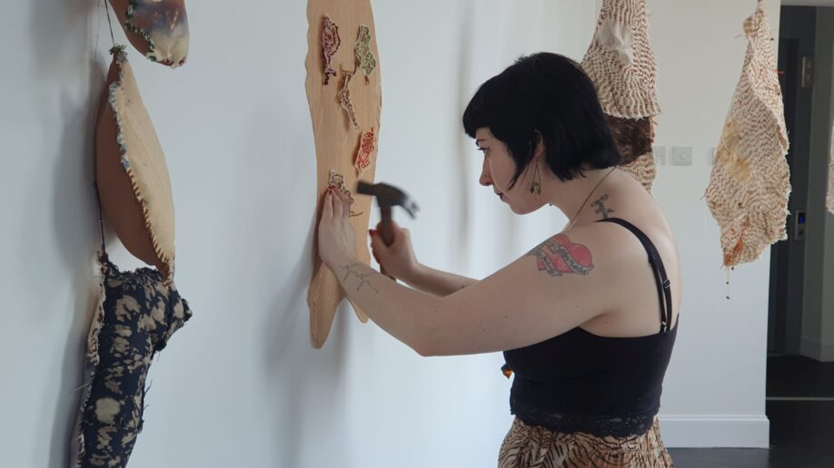 Artist Zana Araki using a hammer while installing fabric artworks in our gallery