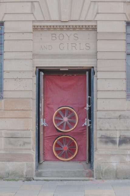 a photo of one of the doors to GWL - the door is open but shows a red sheet of polythene with two fans which are perfrorming an air tightenss test