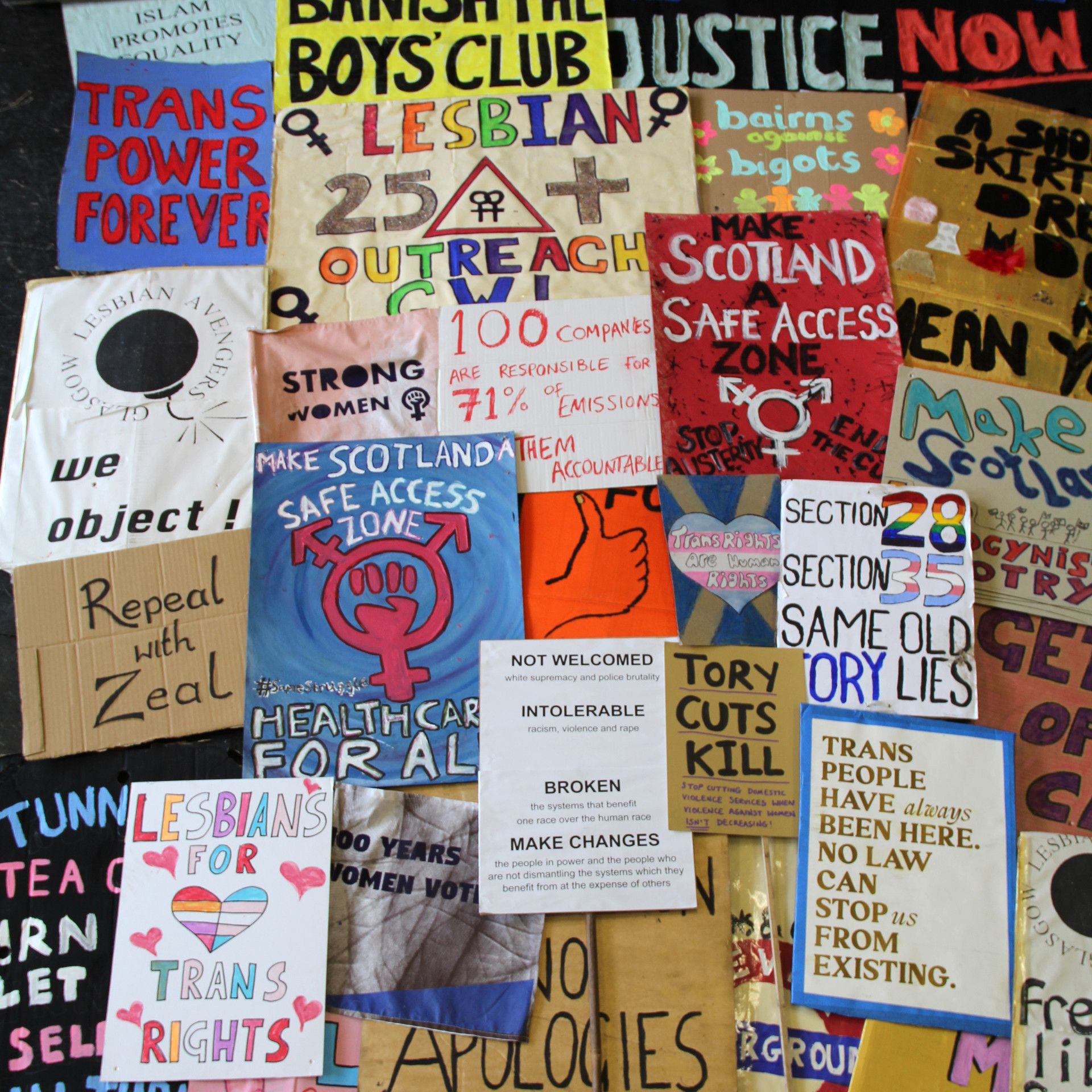 A selection of placards used in protests about women's and LBGTQ+ rights, with slogans including 'Make Scotland a Safe Access Zone', '100 Companies are responsible for 71% of emissions: make them accountable' and 'Lesbians for Trans Rights'