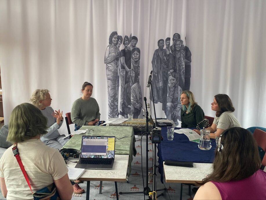 Library staff and volunteers sitting round a recording device in the GWL community room.