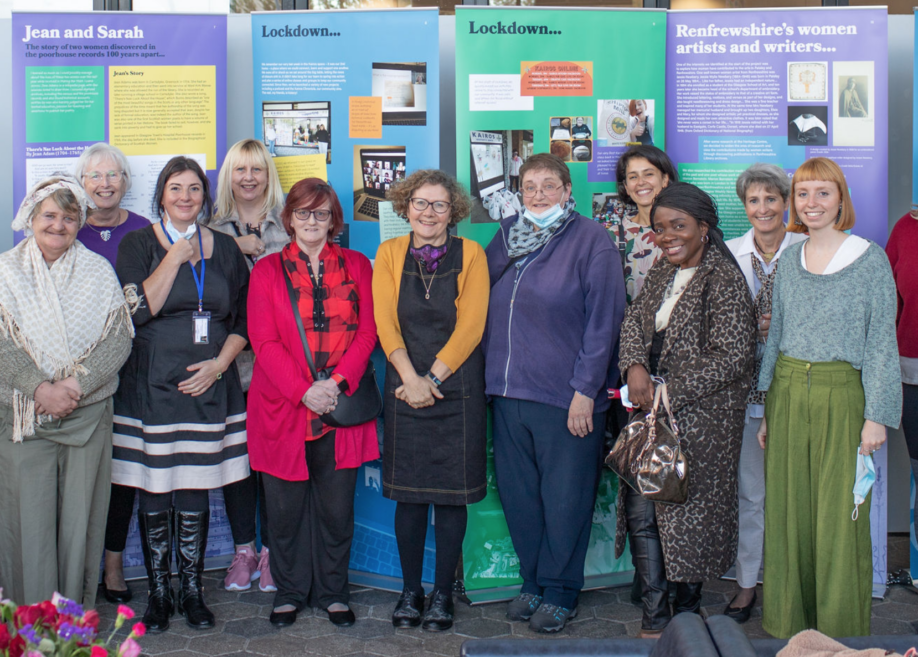 A group of women standing in front of exhibition panels, the women include Morag Smith alongside Kairos Women's group