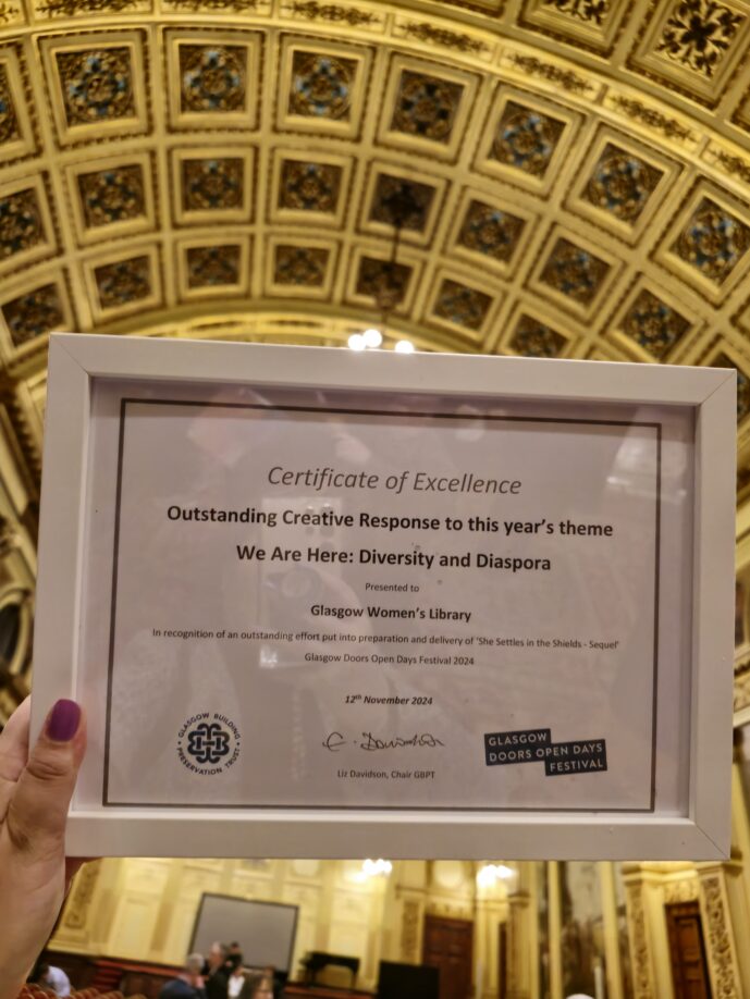 a hand holds up a framed certoficate in the Glasgow City Chambers