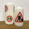 A large candle with several logos from GWL's past, next to a small candle with the 'Women at Work' logo.