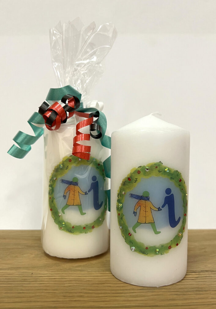 Two candles with a festive-themed version of the GWL logo - one is wrapped with cellophane and tied with ribbons.