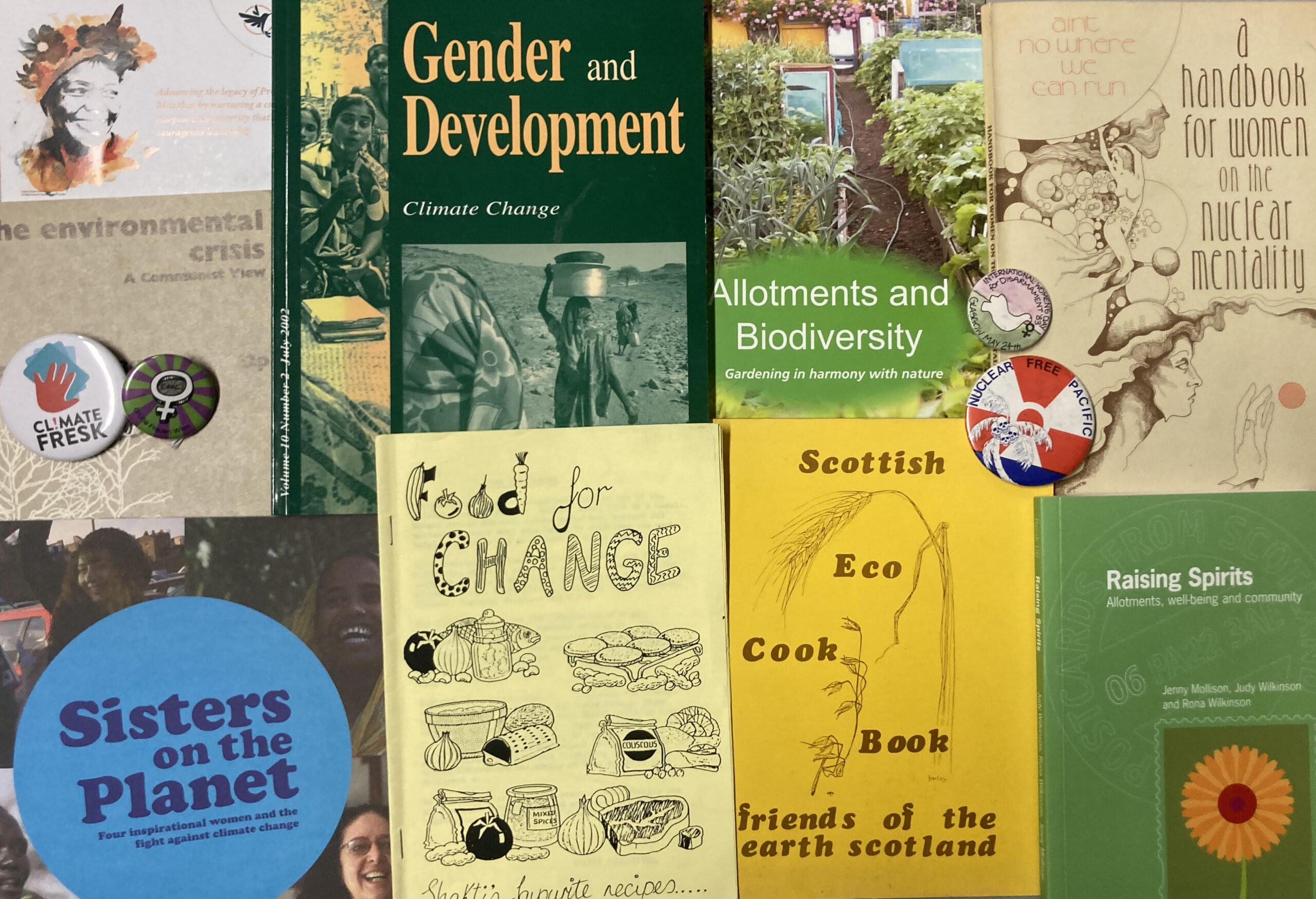 A collection of ecofeminist materials from the GWL archive, including badges, zines and books, laid flat and photographed from above.