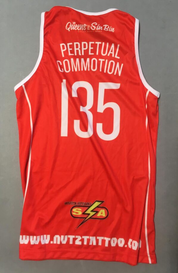 Back of red roller derby uniform top with 'Perpetual Commotion 135' in large white writing on the centre top and the roller derby suppliers/sponsors Queens of the Sin Bin, Skate Attack and Nutz Tattoo at the bottom centre